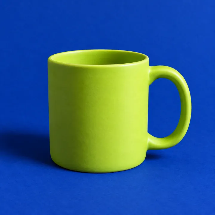 a matte lime mug on ultramarine paper backdrop, studio light